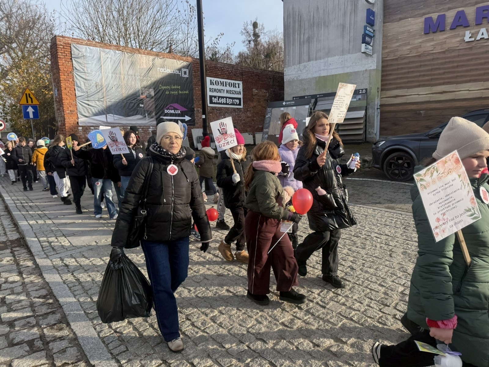 W środę 17.11.2025 nasza szkoła zorganizowała wyjątkowe wydarzenie, które było zaczątkiem podsumowania kampanii „Dzieciństwo bez Przemocy”. Dzień rozpoczął się od radosnego marszu, w którym dzieci grup przedszkolnych z wychowawczyniami oraz uczniowie wraz z nauczycielami przeszli ulicami naszego miasta. Podczas tego wydarzenia dzieci rozdawały mieszkańcom kolorowe maskotki, promując ideę bezpiecznego i szczęśliwego dzieciństwa.
Ważnym punktem dnia było spotkanie w Urzędzie Miasta z panią burmistrz, która serdecznie przyjęła naszych reprezentantów. Rozmowy dotyczyły dalszych działań na rzecz dzieci oraz wspierania inicjatyw mających na celu eliminację przemocy wśród najmłodszych.