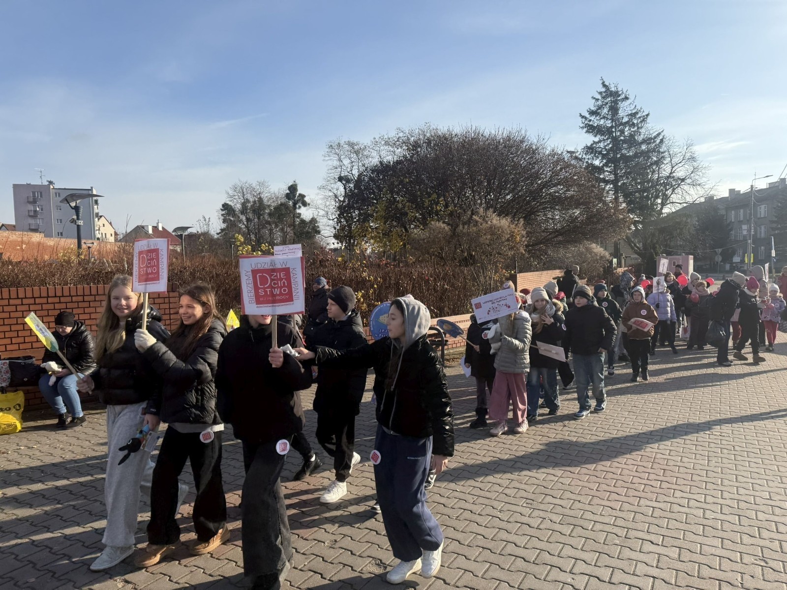 W środę 17.11.2025 nasza szkoła zorganizowała wyjątkowe wydarzenie, które było zaczątkiem podsumowania kampanii „Dzieciństwo bez Przemocy”. Dzień rozpoczął się od radosnego marszu, w którym dzieci grup przedszkolnych z wychowawczyniami oraz uczniowie wraz z nauczycielami przeszli ulicami naszego miasta. Podczas tego wydarzenia dzieci rozdawały mieszkańcom kolorowe maskotki, promując ideę bezpiecznego i szczęśliwego dzieciństwa.
Ważnym punktem dnia było spotkanie w Urzędzie Miasta z panią burmistrz, która serdecznie przyjęła naszych reprezentantów. Rozmowy dotyczyły dalszych działań na rzecz dzieci oraz wspierania inicjatyw mających na celu eliminację przemocy wśród najmłodszych.
