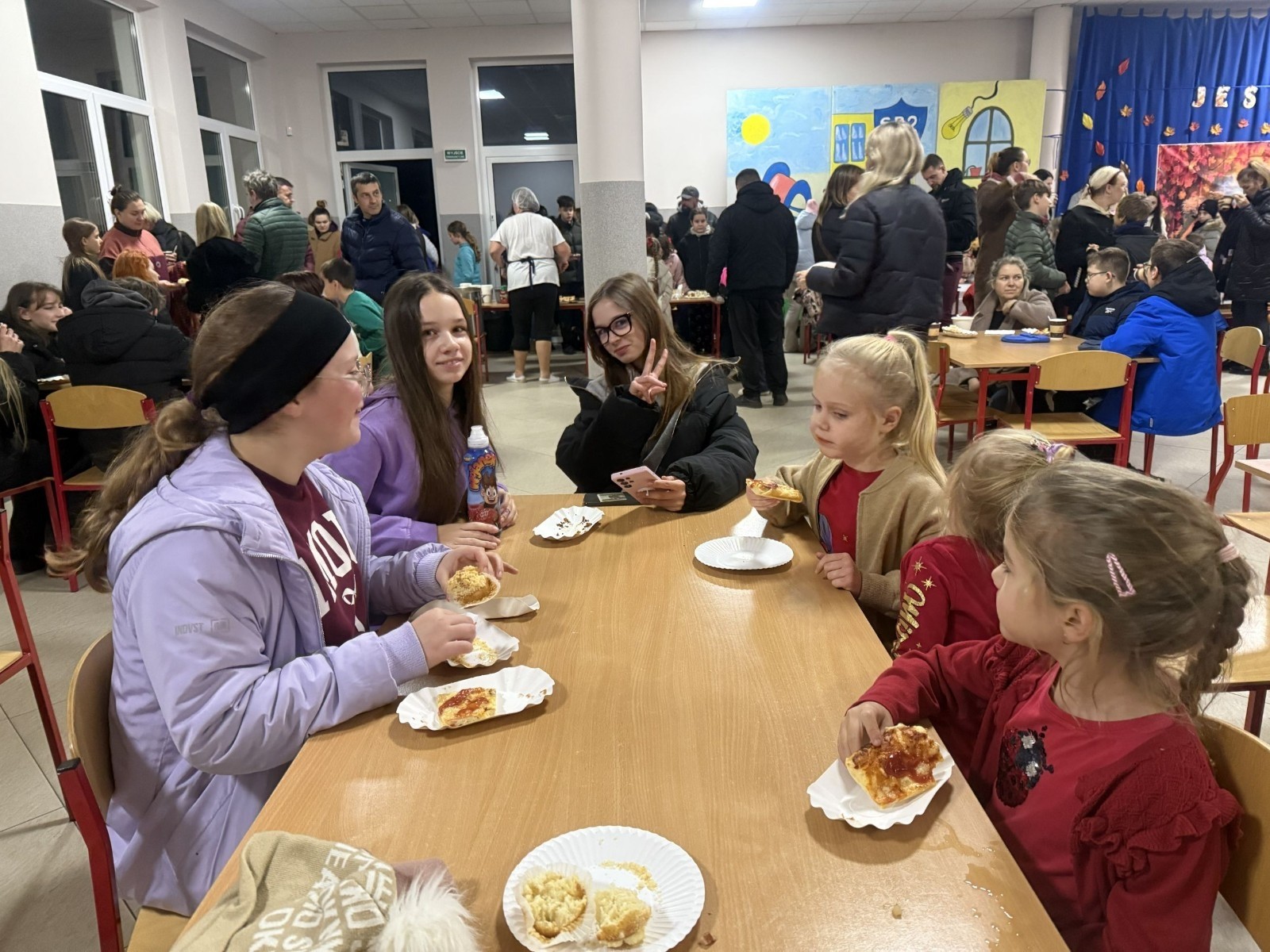 O godzinie 17:00 pod szkołą rozpoczęła się impreza, która zgromadziła około 200 osób. Szkoła została podświetlona na czerwono, co symbolizowało naszą jedność w walce z przemocą. Był to akcent podsumowujący nasze wcześ iej sze  działania w ramach Kampanii Ogólnopolskiej „Dzieciństwo bez Przemocy”. Od października uczniowie uczestniczyli w lekcjach online przygotowanych przez Fundację Dajemy Dzieciom Siłę. Rodzice również zostali objęci wsparciem w postaci webinaru online ww. fudacji.
Uczestnicy mogli wziąć udział w wspólnym śpiewaniu, quizie wiedzy o przemocy oraz tworzeniu „kamieni mocy” – symboli pozytywnej energii i wsparcia. Dodatkowo, w ramach konkursów, przyznano nagrody ufundowane przez Urząd Miejski w Pasłęku.
Ten cudowny czas umilił nam smaczny poczęstunek, w tym grochówka, pizza i ciasta, gorąca kawa i herbatka przygotowany przez panie kucharki i rodziców.
W wydarzeniu uczestniczyli również zaproszeni goście, w tym Burmistrz Pasłęka – pani Elżbieta Wasiuk,  podinspektor KP Pasłęk – pani Agnieszka Bielewicz - Piechowiak oraz przedstawiciel Kuratorium Oświaty w Elblągu – pani Teresa Bednarz, którzy wspierają nasze działania. Ich obecność była dowodem na to, jak ważna jest współpraca lokalnej społeczności w walce z przemocą wobec dzieci. Dziękujemy wszystkim, którzy wzięli udział w tym wyjątkowym dniu oraz przyczynili się do jego organizacji. Razem możemy stworzyć bezpieczne i przyjazne środowisko dla naszych dzieci!
