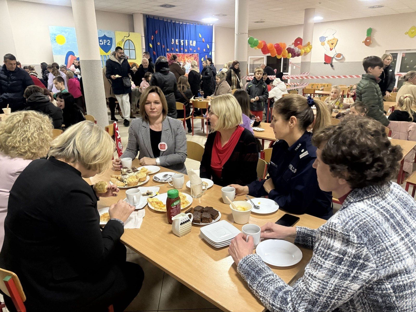 O godzinie 17:00 pod szkołą rozpoczęła się impreza, która zgromadziła około 200 osób. Szkoła została podświetlona na czerwono, co symbolizowało naszą jedność w walce z przemocą. Był to akcent podsumowujący nasze wcześ iej sze  działania w ramach Kampanii Ogólnopolskiej „Dzieciństwo bez Przemocy”. Od października uczniowie uczestniczyli w lekcjach online przygotowanych przez Fundację Dajemy Dzieciom Siłę. Rodzice również zostali objęci wsparciem w postaci webinaru online ww. fudacji.
Uczestnicy mogli wziąć udział w wspólnym śpiewaniu, quizie wiedzy o przemocy oraz tworzeniu „kamieni mocy” – symboli pozytywnej energii i wsparcia. Dodatkowo, w ramach konkursów, przyznano nagrody ufundowane przez Urząd Miejski w Pasłęku.
Ten cudowny czas umilił nam smaczny poczęstunek, w tym grochówka, pizza i ciasta, gorąca kawa i herbatka przygotowany przez panie kucharki i rodziców.
W wydarzeniu uczestniczyli również zaproszeni goście, w tym Burmistrz Pasłęka – pani Elżbieta Wasiuk,  podinspektor KP Pasłęk – pani Agnieszka Bielewicz - Piechowiak oraz przedstawiciel Kuratorium Oświaty w Elblągu – pani Teresa Bednarz, którzy wspierają nasze działania. Ich obecność była dowodem na to, jak ważna jest współpraca lokalnej społeczności w walce z przemocą wobec dzieci. Dziękujemy wszystkim, którzy wzięli udział w tym wyjątkowym dniu oraz przyczynili się do jego organizacji. Razem możemy stworzyć bezpieczne i przyjazne środowisko dla naszych dzieci!
