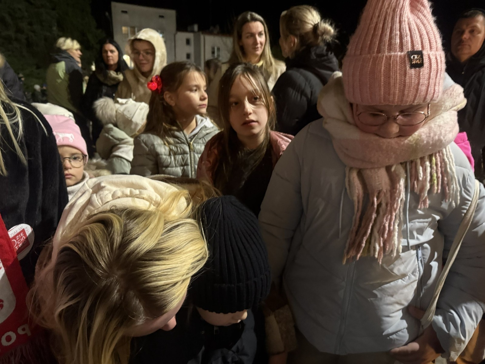 O godzinie 17:00 pod szkołą rozpoczęła się impreza, która zgromadziła około 200 osób. Szkoła została podświetlona na czerwono, co symbolizowało naszą jedność w walce z przemocą. Był to akcent podsumowujący nasze wcześ iej sze  działania w ramach Kampanii Ogólnopolskiej „Dzieciństwo bez Przemocy”. Od października uczniowie uczestniczyli w lekcjach online przygotowanych przez Fundację Dajemy Dzieciom Siłę. Rodzice również zostali objęci wsparciem w postaci webinaru online ww. fudacji.
Uczestnicy mogli wziąć udział w wspólnym śpiewaniu, quizie wiedzy o przemocy oraz tworzeniu „kamieni mocy” – symboli pozytywnej energii i wsparcia. Dodatkowo, w ramach konkursów, przyznano nagrody ufundowane przez Urząd Miejski w Pasłęku.
Ten cudowny czas umilił nam smaczny poczęstunek, w tym grochówka, pizza i ciasta, gorąca kawa i herbatka przygotowany przez panie kucharki i rodziców.
W wydarzeniu uczestniczyli również zaproszeni goście, w tym Burmistrz Pasłęka – pani Elżbieta Wasiuk,  podinspektor KP Pasłęk – pani Agnieszka Bielewicz - Piechowiak oraz przedstawiciel Kuratorium Oświaty w Elblągu – pani Teresa Bednarz, którzy wspierają nasze działania. Ich obecność była dowodem na to, jak ważna jest współpraca lokalnej społeczności w walce z przemocą wobec dzieci. Dziękujemy wszystkim, którzy wzięli udział w tym wyjątkowym dniu oraz przyczynili się do jego organizacji. Razem możemy stworzyć bezpieczne i przyjazne środowisko dla naszych dzieci!
