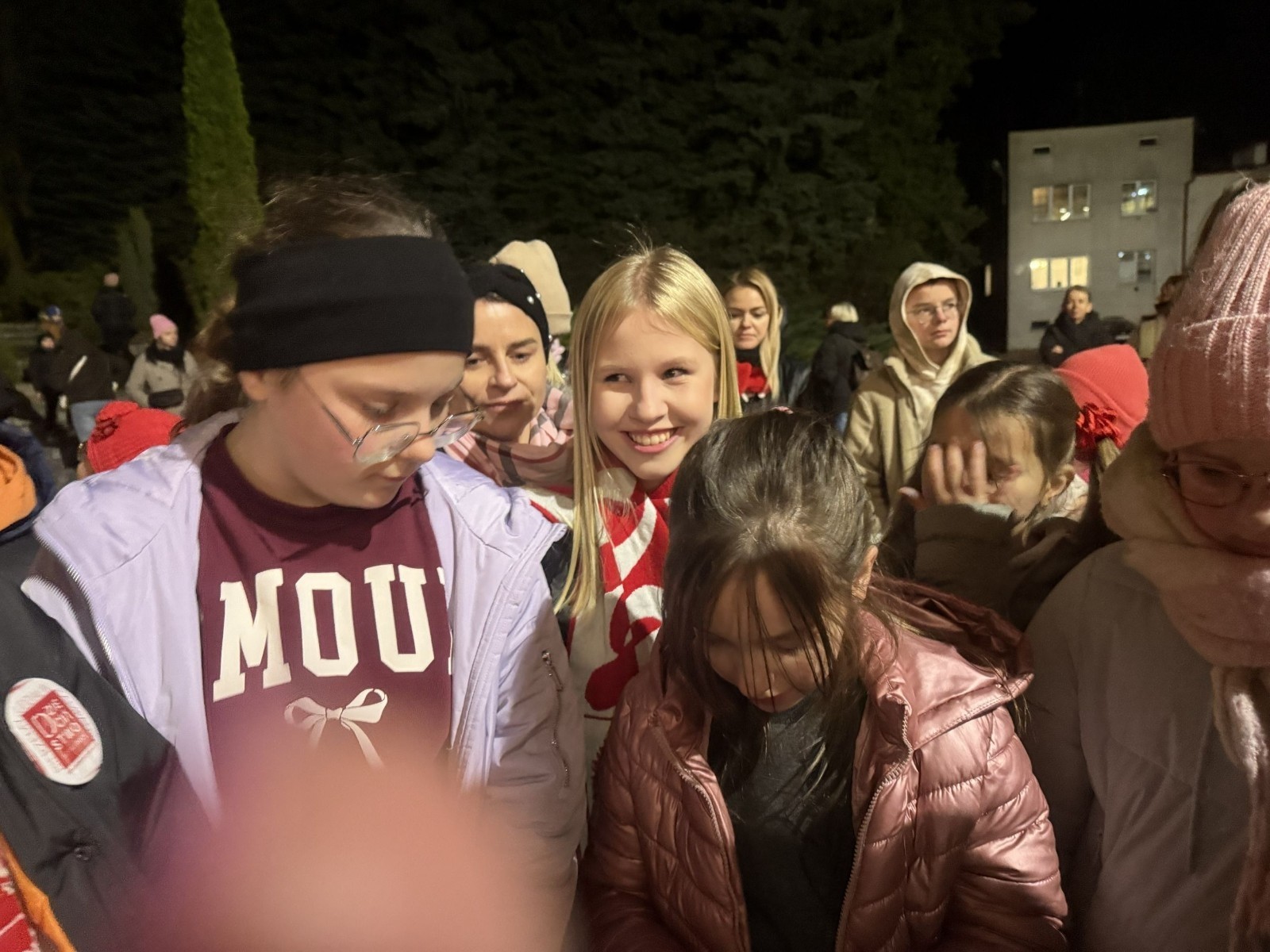 O godzinie 17:00 pod szkołą rozpoczęła się impreza, która zgromadziła około 200 osób. Szkoła została podświetlona na czerwono, co symbolizowało naszą jedność w walce z przemocą. Był to akcent podsumowujący nasze wcześ iej sze  działania w ramach Kampanii Ogólnopolskiej „Dzieciństwo bez Przemocy”. Od października uczniowie uczestniczyli w lekcjach online przygotowanych przez Fundację Dajemy Dzieciom Siłę. Rodzice również zostali objęci wsparciem w postaci webinaru online ww. fudacji.
Uczestnicy mogli wziąć udział w wspólnym śpiewaniu, quizie wiedzy o przemocy oraz tworzeniu „kamieni mocy” – symboli pozytywnej energii i wsparcia. Dodatkowo, w ramach konkursów, przyznano nagrody ufundowane przez Urząd Miejski w Pasłęku.
Ten cudowny czas umilił nam smaczny poczęstunek, w tym grochówka, pizza i ciasta, gorąca kawa i herbatka przygotowany przez panie kucharki i rodziców.
W wydarzeniu uczestniczyli również zaproszeni goście, w tym Burmistrz Pasłęka – pani Elżbieta Wasiuk,  podinspektor KP Pasłęk – pani Agnieszka Bielewicz - Piechowiak oraz przedstawiciel Kuratorium Oświaty w Elblągu – pani Teresa Bednarz, którzy wspierają nasze działania. Ich obecność była dowodem na to, jak ważna jest współpraca lokalnej społeczności w walce z przemocą wobec dzieci. Dziękujemy wszystkim, którzy wzięli udział w tym wyjątkowym dniu oraz przyczynili się do jego organizacji. Razem możemy stworzyć bezpieczne i przyjazne środowisko dla naszych dzieci!
