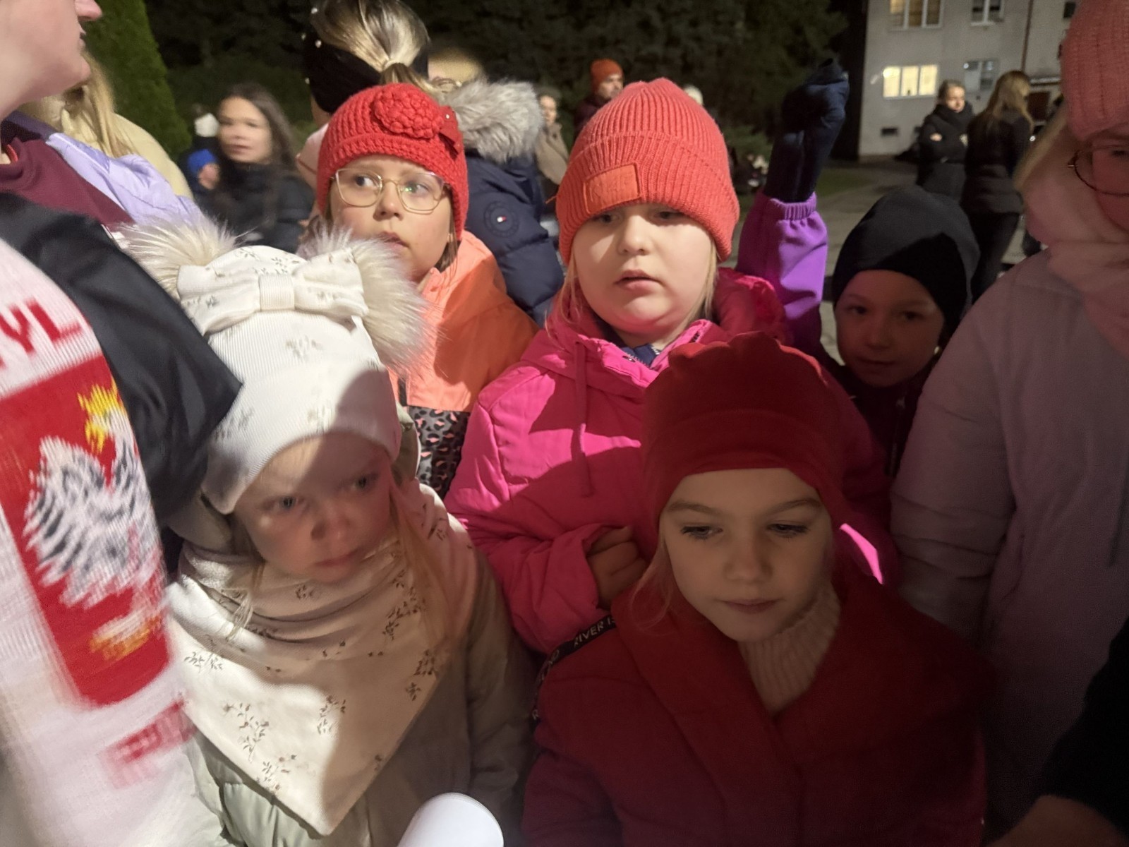 O godzinie 17:00 pod szkołą rozpoczęła się impreza, która zgromadziła około 200 osób. Szkoła została podświetlona na czerwono, co symbolizowało naszą jedność w walce z przemocą. Był to akcent podsumowujący nasze wcześ iej sze  działania w ramach Kampanii Ogólnopolskiej „Dzieciństwo bez Przemocy”. Od października uczniowie uczestniczyli w lekcjach online przygotowanych przez Fundację Dajemy Dzieciom Siłę. Rodzice również zostali objęci wsparciem w postaci webinaru online ww. fudacji.
Uczestnicy mogli wziąć udział w wspólnym śpiewaniu, quizie wiedzy o przemocy oraz tworzeniu „kamieni mocy” – symboli pozytywnej energii i wsparcia. Dodatkowo, w ramach konkursów, przyznano nagrody ufundowane przez Urząd Miejski w Pasłęku.
Ten cudowny czas umilił nam smaczny poczęstunek, w tym grochówka, pizza i ciasta, gorąca kawa i herbatka przygotowany przez panie kucharki i rodziców.
W wydarzeniu uczestniczyli również zaproszeni goście, w tym Burmistrz Pasłęka – pani Elżbieta Wasiuk,  podinspektor KP Pasłęk – pani Agnieszka Bielewicz - Piechowiak oraz przedstawiciel Kuratorium Oświaty w Elblągu – pani Teresa Bednarz, którzy wspierają nasze działania. Ich obecność była dowodem na to, jak ważna jest współpraca lokalnej społeczności w walce z przemocą wobec dzieci. Dziękujemy wszystkim, którzy wzięli udział w tym wyjątkowym dniu oraz przyczynili się do jego organizacji. Razem możemy stworzyć bezpieczne i przyjazne środowisko dla naszych dzieci!
