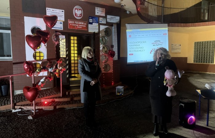 O godzinie 17:00 pod szkołą rozpoczęła się impreza, która zgromadziła około 200 osób. Szkoła została podświetlona na czerwono, co symbolizowało naszą jedność w walce z przemocą. Był to akcent podsumowujący nasze wcześ iej sze  działania w ramach Kampanii Ogólnopolskiej „Dzieciństwo bez Przemocy”. Od października uczniowie uczestniczyli w lekcjach online przygotowanych przez Fundację Dajemy Dzieciom Siłę. Rodzice również zostali objęci wsparciem w postaci webinaru online ww. fudacji.
Uczestnicy mogli wziąć udział w wspólnym śpiewaniu, quizie wiedzy o przemocy oraz tworzeniu „kamieni mocy” – symboli pozytywnej energii i wsparcia. Dodatkowo, w ramach konkursów, przyznano nagrody ufundowane przez Urząd Miejski w Pasłęku.
Ten cudowny czas umilił nam smaczny poczęstunek, w tym grochówka, pizza i ciasta, gorąca kawa i herbatka przygotowany przez panie kucharki i rodziców.
W wydarzeniu uczestniczyli również zaproszeni goście, w tym Burmistrz Pasłęka – pani Elżbieta Wasiuk,  podinspektor KP Pasłęk – pani Agnieszka Bielewicz - Piechowiak oraz przedstawiciel Kuratorium Oświaty w Elblągu – pani Teresa Bednarz, którzy wspierają nasze działania. Ich obecność była dowodem na to, jak ważna jest współpraca lokalnej społeczności w walce z przemocą wobec dzieci. Dziękujemy wszystkim, którzy wzięli udział w tym wyjątkowym dniu oraz przyczynili się do jego organizacji. Razem możemy stworzyć bezpieczne i przyjazne środowisko dla naszych dzieci!
