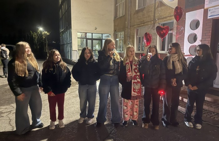 O godzinie 17:00 pod szkołą rozpoczęła się impreza, która zgromadziła około 200 osób. Szkoła została podświetlona na czerwono, co symbolizowało naszą jedność w walce z przemocą. Był to akcent podsumowujący nasze wcześ iej sze  działania w ramach Kampanii Ogólnopolskiej „Dzieciństwo bez Przemocy”. Od października uczniowie uczestniczyli w lekcjach online przygotowanych przez Fundację Dajemy Dzieciom Siłę. Rodzice również zostali objęci wsparciem w postaci webinaru online ww. fudacji.
Uczestnicy mogli wziąć udział w wspólnym śpiewaniu, quizie wiedzy o przemocy oraz tworzeniu „kamieni mocy” – symboli pozytywnej energii i wsparcia. Dodatkowo, w ramach konkursów, przyznano nagrody ufundowane przez Urząd Miejski w Pasłęku.
Ten cudowny czas umilił nam smaczny poczęstunek, w tym grochówka, pizza i ciasta, gorąca kawa i herbatka przygotowany przez panie kucharki i rodziców.
W wydarzeniu uczestniczyli również zaproszeni goście, w tym Burmistrz Pasłęka – pani Elżbieta Wasiuk,  podinspektor KP Pasłęk – pani Agnieszka Bielewicz - Piechowiak oraz przedstawiciel Kuratorium Oświaty w Elblągu – pani Teresa Bednarz, którzy wspierają nasze działania. Ich obecność była dowodem na to, jak ważna jest współpraca lokalnej społeczności w walce z przemocą wobec dzieci. Dziękujemy wszystkim, którzy wzięli udział w tym wyjątkowym dniu oraz przyczynili się do jego organizacji. Razem możemy stworzyć bezpieczne i przyjazne środowisko dla naszych dzieci!
