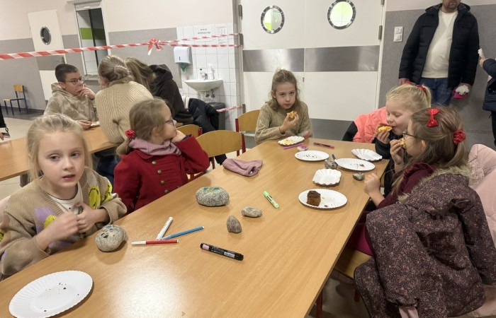 O godzinie 17:00 pod szkołą rozpoczęła się impreza, która zgromadziła około 200 osób. Szkoła została podświetlona na czerwono, co symbolizowało naszą jedność w walce z przemocą. Był to akcent podsumowujący nasze wcześ iej sze  działania w ramach Kampanii Ogólnopolskiej „Dzieciństwo bez Przemocy”. Od października uczniowie uczestniczyli w lekcjach online przygotowanych przez Fundację Dajemy Dzieciom Siłę. Rodzice również zostali objęci wsparciem w postaci webinaru online ww. fudacji.
Uczestnicy mogli wziąć udział w wspólnym śpiewaniu, quizie wiedzy o przemocy oraz tworzeniu „kamieni mocy” – symboli pozytywnej energii i wsparcia. Dodatkowo, w ramach konkursów, przyznano nagrody ufundowane przez Urząd Miejski w Pasłęku.
Ten cudowny czas umilił nam smaczny poczęstunek, w tym grochówka, pizza i ciasta, gorąca kawa i herbatka przygotowany przez panie kucharki i rodziców.
W wydarzeniu uczestniczyli również zaproszeni goście, w tym Burmistrz Pasłęka – pani Elżbieta Wasiuk,  podinspektor KP Pasłęk – pani Agnieszka Bielewicz - Piechowiak oraz przedstawiciel Kuratorium Oświaty w Elblągu – pani Teresa Bednarz, którzy wspierają nasze działania. Ich obecność była dowodem na to, jak ważna jest współpraca lokalnej społeczności w walce z przemocą wobec dzieci. Dziękujemy wszystkim, którzy wzięli udział w tym wyjątkowym dniu oraz przyczynili się do jego organizacji. Razem możemy stworzyć bezpieczne i przyjazne środowisko dla naszych dzieci!
