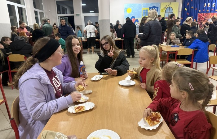 O godzinie 17:00 pod szkołą rozpoczęła się impreza, która zgromadziła około 200 osób. Szkoła została podświetlona na czerwono, co symbolizowało naszą jedność w walce z przemocą. Był to akcent podsumowujący nasze wcześ iej sze  działania w ramach Kampanii Ogólnopolskiej „Dzieciństwo bez Przemocy”. Od października uczniowie uczestniczyli w lekcjach online przygotowanych przez Fundację Dajemy Dzieciom Siłę. Rodzice również zostali objęci wsparciem w postaci webinaru online ww. fudacji.
Uczestnicy mogli wziąć udział w wspólnym śpiewaniu, quizie wiedzy o przemocy oraz tworzeniu „kamieni mocy” – symboli pozytywnej energii i wsparcia. Dodatkowo, w ramach konkursów, przyznano nagrody ufundowane przez Urząd Miejski w Pasłęku.
Ten cudowny czas umilił nam smaczny poczęstunek, w tym grochówka, pizza i ciasta, gorąca kawa i herbatka przygotowany przez panie kucharki i rodziców.
W wydarzeniu uczestniczyli również zaproszeni goście, w tym Burmistrz Pasłęka – pani Elżbieta Wasiuk,  podinspektor KP Pasłęk – pani Agnieszka Bielewicz - Piechowiak oraz przedstawiciel Kuratorium Oświaty w Elblągu – pani Teresa Bednarz, którzy wspierają nasze działania. Ich obecność była dowodem na to, jak ważna jest współpraca lokalnej społeczności w walce z przemocą wobec dzieci. Dziękujemy wszystkim, którzy wzięli udział w tym wyjątkowym dniu oraz przyczynili się do jego organizacji. Razem możemy stworzyć bezpieczne i przyjazne środowisko dla naszych dzieci!
