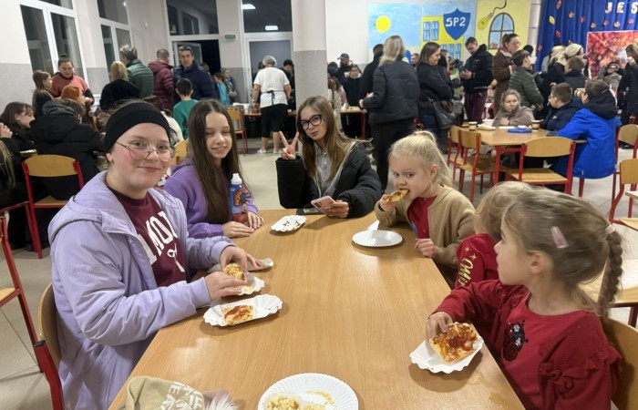 O godzinie 17:00 pod szkołą rozpoczęła się impreza, która zgromadziła około 200 osób. Szkoła została podświetlona na czerwono, co symbolizowało naszą jedność w walce z przemocą. Był to akcent podsumowujący nasze wcześ iej sze  działania w ramach Kampanii Ogólnopolskiej „Dzieciństwo bez Przemocy”. Od października uczniowie uczestniczyli w lekcjach online przygotowanych przez Fundację Dajemy Dzieciom Siłę. Rodzice również zostali objęci wsparciem w postaci webinaru online ww. fudacji.
Uczestnicy mogli wziąć udział w wspólnym śpiewaniu, quizie wiedzy o przemocy oraz tworzeniu „kamieni mocy” – symboli pozytywnej energii i wsparcia. Dodatkowo, w ramach konkursów, przyznano nagrody ufundowane przez Urząd Miejski w Pasłęku.
Ten cudowny czas umilił nam smaczny poczęstunek, w tym grochówka, pizza i ciasta, gorąca kawa i herbatka przygotowany przez panie kucharki i rodziców.
W wydarzeniu uczestniczyli również zaproszeni goście, w tym Burmistrz Pasłęka – pani Elżbieta Wasiuk,  podinspektor KP Pasłęk – pani Agnieszka Bielewicz - Piechowiak oraz przedstawiciel Kuratorium Oświaty w Elblągu – pani Teresa Bednarz, którzy wspierają nasze działania. Ich obecność była dowodem na to, jak ważna jest współpraca lokalnej społeczności w walce z przemocą wobec dzieci. Dziękujemy wszystkim, którzy wzięli udział w tym wyjątkowym dniu oraz przyczynili się do jego organizacji. Razem możemy stworzyć bezpieczne i przyjazne środowisko dla naszych dzieci!
