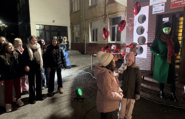 O godzinie 17:00 pod szkołą rozpoczęła się impreza, która zgromadziła około 200 osób. Szkoła została podświetlona na czerwono, co symbolizowało naszą jedność w walce z przemocą. Był to akcent podsumowujący nasze wcześ iej sze  działania w ramach Kampanii Ogólnopolskiej „Dzieciństwo bez Przemocy”. Od października uczniowie uczestniczyli w lekcjach online przygotowanych przez Fundację Dajemy Dzieciom Siłę. Rodzice również zostali objęci wsparciem w postaci webinaru online ww. fudacji.
Uczestnicy mogli wziąć udział w wspólnym śpiewaniu, quizie wiedzy o przemocy oraz tworzeniu „kamieni mocy” – symboli pozytywnej energii i wsparcia. Dodatkowo, w ramach konkursów, przyznano nagrody ufundowane przez Urząd Miejski w Pasłęku.
Ten cudowny czas umilił nam smaczny poczęstunek, w tym grochówka, pizza i ciasta, gorąca kawa i herbatka przygotowany przez panie kucharki i rodziców.
W wydarzeniu uczestniczyli również zaproszeni goście, w tym Burmistrz Pasłęka – pani Elżbieta Wasiuk,  podinspektor KP Pasłęk – pani Agnieszka Bielewicz - Piechowiak oraz przedstawiciel Kuratorium Oświaty w Elblągu – pani Teresa Bednarz, którzy wspierają nasze działania. Ich obecność była dowodem na to, jak ważna jest współpraca lokalnej społeczności w walce z przemocą wobec dzieci. Dziękujemy wszystkim, którzy wzięli udział w tym wyjątkowym dniu oraz przyczynili się do jego organizacji. Razem możemy stworzyć bezpieczne i przyjazne środowisko dla naszych dzieci!
