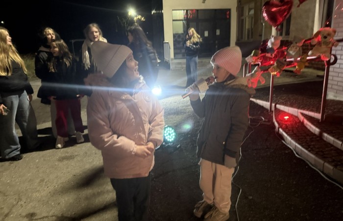 O godzinie 17:00 pod szkołą rozpoczęła się impreza, która zgromadziła około 200 osób. Szkoła została podświetlona na czerwono, co symbolizowało naszą jedność w walce z przemocą. Był to akcent podsumowujący nasze wcześ iej sze  działania w ramach Kampanii Ogólnopolskiej „Dzieciństwo bez Przemocy”. Od października uczniowie uczestniczyli w lekcjach online przygotowanych przez Fundację Dajemy Dzieciom Siłę. Rodzice również zostali objęci wsparciem w postaci webinaru online ww. fudacji.
Uczestnicy mogli wziąć udział w wspólnym śpiewaniu, quizie wiedzy o przemocy oraz tworzeniu „kamieni mocy” – symboli pozytywnej energii i wsparcia. Dodatkowo, w ramach konkursów, przyznano nagrody ufundowane przez Urząd Miejski w Pasłęku.
Ten cudowny czas umilił nam smaczny poczęstunek, w tym grochówka, pizza i ciasta, gorąca kawa i herbatka przygotowany przez panie kucharki i rodziców.
W wydarzeniu uczestniczyli również zaproszeni goście, w tym Burmistrz Pasłęka – pani Elżbieta Wasiuk,  podinspektor KP Pasłęk – pani Agnieszka Bielewicz - Piechowiak oraz przedstawiciel Kuratorium Oświaty w Elblągu – pani Teresa Bednarz, którzy wspierają nasze działania. Ich obecność była dowodem na to, jak ważna jest współpraca lokalnej społeczności w walce z przemocą wobec dzieci. Dziękujemy wszystkim, którzy wzięli udział w tym wyjątkowym dniu oraz przyczynili się do jego organizacji. Razem możemy stworzyć bezpieczne i przyjazne środowisko dla naszych dzieci!
