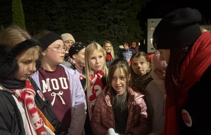 O godzinie 17:00 pod szkołą rozpoczęła się impreza, która zgromadziła około 200 osób. Szkoła została podświetlona na czerwono, co symbolizowało naszą jedność w walce z przemocą. Był to akcent podsumowujący nasze wcześ iej sze  działania w ramach Kampanii Ogólnopolskiej „Dzieciństwo bez Przemocy”. Od października uczniowie uczestniczyli w lekcjach online przygotowanych przez Fundację Dajemy Dzieciom Siłę. Rodzice również zostali objęci wsparciem w postaci webinaru online ww. fudacji.
Uczestnicy mogli wziąć udział w wspólnym śpiewaniu, quizie wiedzy o przemocy oraz tworzeniu „kamieni mocy” – symboli pozytywnej energii i wsparcia. Dodatkowo, w ramach konkursów, przyznano nagrody ufundowane przez Urząd Miejski w Pasłęku.
Ten cudowny czas umilił nam smaczny poczęstunek, w tym grochówka, pizza i ciasta, gorąca kawa i herbatka przygotowany przez panie kucharki i rodziców.
W wydarzeniu uczestniczyli również zaproszeni goście, w tym Burmistrz Pasłęka – pani Elżbieta Wasiuk,  podinspektor KP Pasłęk – pani Agnieszka Bielewicz - Piechowiak oraz przedstawiciel Kuratorium Oświaty w Elblągu – pani Teresa Bednarz, którzy wspierają nasze działania. Ich obecność była dowodem na to, jak ważna jest współpraca lokalnej społeczności w walce z przemocą wobec dzieci. Dziękujemy wszystkim, którzy wzięli udział w tym wyjątkowym dniu oraz przyczynili się do jego organizacji. Razem możemy stworzyć bezpieczne i przyjazne środowisko dla naszych dzieci!
