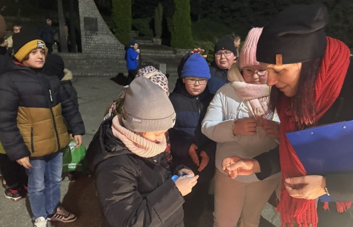 O godzinie 17:00 pod szkołą rozpoczęła się impreza, która zgromadziła około 200 osób. Szkoła została podświetlona na czerwono, co symbolizowało naszą jedność w walce z przemocą. Był to akcent podsumowujący nasze wcześ iej sze  działania w ramach Kampanii Ogólnopolskiej „Dzieciństwo bez Przemocy”. Od października uczniowie uczestniczyli w lekcjach online przygotowanych przez Fundację Dajemy Dzieciom Siłę. Rodzice również zostali objęci wsparciem w postaci webinaru online ww. fudacji.
Uczestnicy mogli wziąć udział w wspólnym śpiewaniu, quizie wiedzy o przemocy oraz tworzeniu „kamieni mocy” – symboli pozytywnej energii i wsparcia. Dodatkowo, w ramach konkursów, przyznano nagrody ufundowane przez Urząd Miejski w Pasłęku.
Ten cudowny czas umilił nam smaczny poczęstunek, w tym grochówka, pizza i ciasta, gorąca kawa i herbatka przygotowany przez panie kucharki i rodziców.
W wydarzeniu uczestniczyli również zaproszeni goście, w tym Burmistrz Pasłęka – pani Elżbieta Wasiuk,  podinspektor KP Pasłęk – pani Agnieszka Bielewicz - Piechowiak oraz przedstawiciel Kuratorium Oświaty w Elblągu – pani Teresa Bednarz, którzy wspierają nasze działania. Ich obecność była dowodem na to, jak ważna jest współpraca lokalnej społeczności w walce z przemocą wobec dzieci. Dziękujemy wszystkim, którzy wzięli udział w tym wyjątkowym dniu oraz przyczynili się do jego organizacji. Razem możemy stworzyć bezpieczne i przyjazne środowisko dla naszych dzieci!
