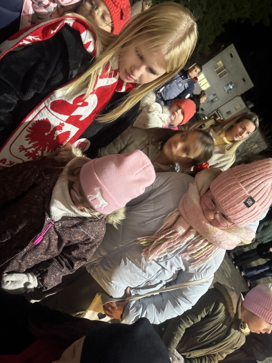 O godzinie 17:00 pod szkołą rozpoczęła się impreza, która zgromadziła około 200 osób. Szkoła została podświetlona na czerwono, co symbolizowało naszą jedność w walce z przemocą. Był to akcent podsumowujący nasze wcześ iej sze  działania w ramach Kampanii Ogólnopolskiej „Dzieciństwo bez Przemocy”. Od października uczniowie uczestniczyli w lekcjach online przygotowanych przez Fundację Dajemy Dzieciom Siłę. Rodzice również zostali objęci wsparciem w postaci webinaru online ww. fudacji.
Uczestnicy mogli wziąć udział w wspólnym śpiewaniu, quizie wiedzy o przemocy oraz tworzeniu „kamieni mocy” – symboli pozytywnej energii i wsparcia. Dodatkowo, w ramach konkursów, przyznano nagrody ufundowane przez Urząd Miejski w Pasłęku.
Ten cudowny czas umilił nam smaczny poczęstunek, w tym grochówka, pizza i ciasta, gorąca kawa i herbatka przygotowany przez panie kucharki i rodziców.
W wydarzeniu uczestniczyli również zaproszeni goście, w tym Burmistrz Pasłęka – pani Elżbieta Wasiuk,  podinspektor KP Pasłęk – pani Agnieszka Bielewicz - Piechowiak oraz przedstawiciel Kuratorium Oświaty w Elblągu – pani Teresa Bednarz, którzy wspierają nasze działania. Ich obecność była dowodem na to, jak ważna jest współpraca lokalnej społeczności w walce z przemocą wobec dzieci. Dziękujemy wszystkim, którzy wzięli udział w tym wyjątkowym dniu oraz przyczynili się do jego organizacji. Razem możemy stworzyć bezpieczne i przyjazne środowisko dla naszych dzieci!
