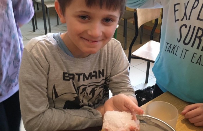 Podczas zajęć projektowych przyrodniczych wykonywaliśmy proste i bezpieczne doświadczenia. Jednym z doświadczeń, które wybrali uczniowie było: Jak wykonać sztuczny śnieg? Do wykonania takiego doświadczenia potrzebujemy: pieluchy (pampersy) rozkładamy i rozcinamy środek tak, aby ze środka wyrzucić do naszej miseczki drobne kuleczki. Te kuleczki to superchłonny żel doskonały do stworzenia śniegu. Kulki pochłaniają wilgoć w masie blisko 30 razy większej od własnej, tym sposobem już z jednej pieluchy możemy zrobić sporą ilość śniegu. Wykonany sztuczny śnieg uczniowie mogą dotknąć, pobawić się jego konsystencją. Jest bardzo miły w dotyku.